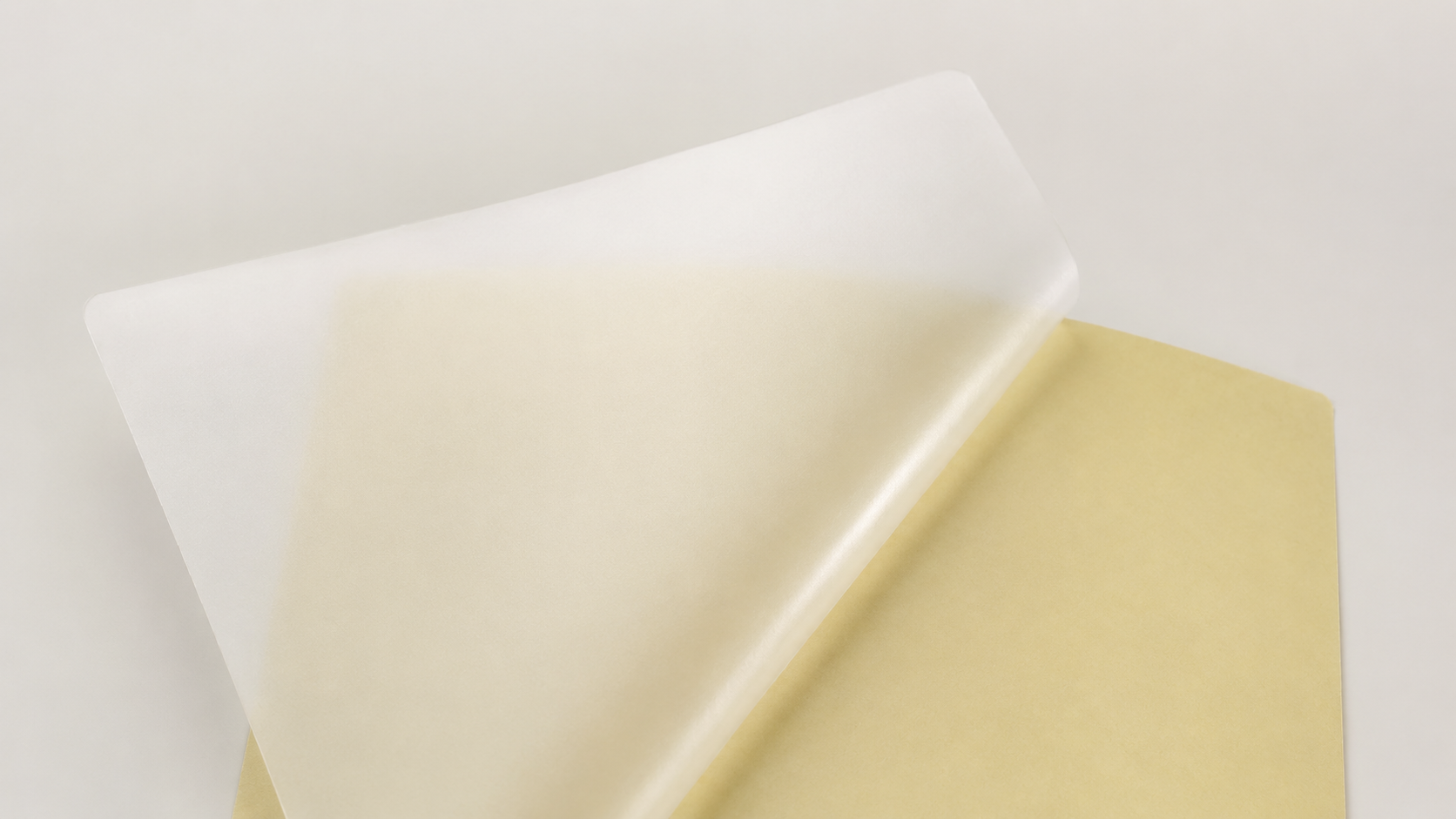 Translucent frosted self-adhesive film lifted from its pale yellow release liner